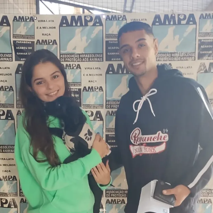 Cachorrinho de porte pequeno recebendo carinho no colo do seu novo tutor
